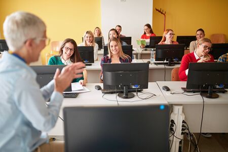 Smiling University students sitting together at table using computer in class.の写真素材
