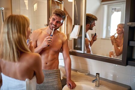 Cheerful couple in bathroom brushing teethの写真素材