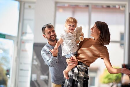 Happy man and woman with smiling child girl in store shopping