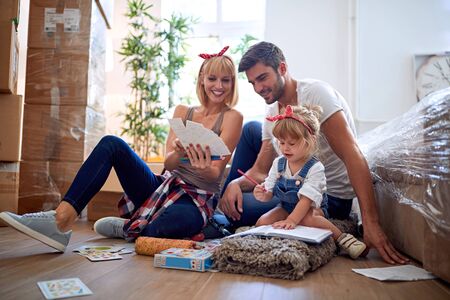 Young mother and father with a toddler girl moving in new homeの写真素材