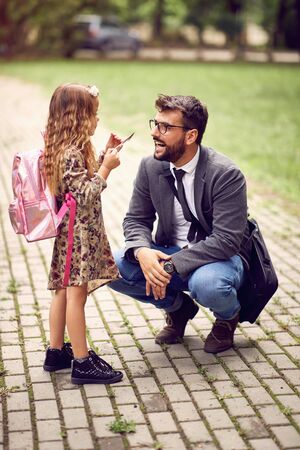 Smiling business father taking child to primary school.の写真素材