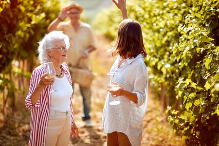 Smiling mother and daughter on autumn vineyard tasting wineの写真素材