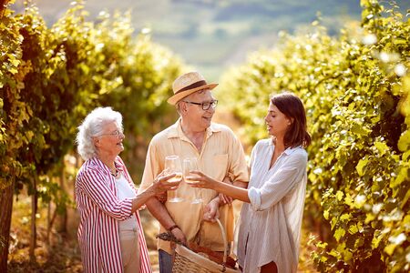 Smiling family on autumn vineyard tasting wine