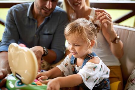 Girl playing with toy while parents looking herの写真素材