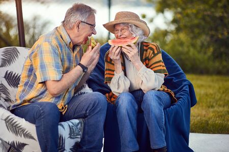 Smiling mature couple on romantic vacation eating watermelonの写真素材