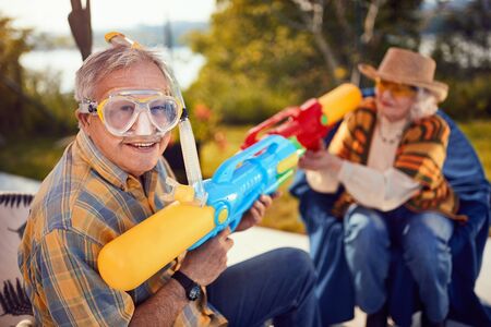 Smiling Senior couple on crazy vacation  playing with water gun