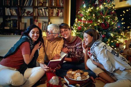 Cheerful mather  and her happy daughter together for Christmas in front of a decorated x-mas treeの写真素材