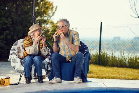 Smiling couple friends having fun together and eat watermelonの写真素材