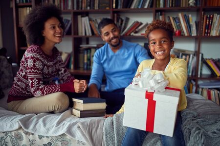 Smiling parents surprising happy daughter with a Christmas present.の写真素材