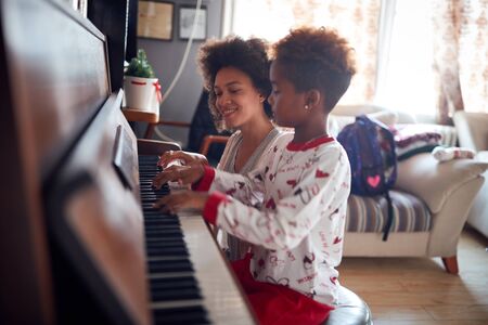 family at Christmas play music on piano.Smiling Mother with child girl on Christmas play musicの写真素材