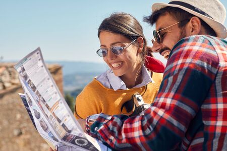 Choose a destination at travel.Smiling man and woman traveling and reading map in city