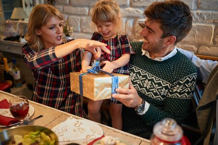 cheerful and happy family open gifts at christmas traditional dinner