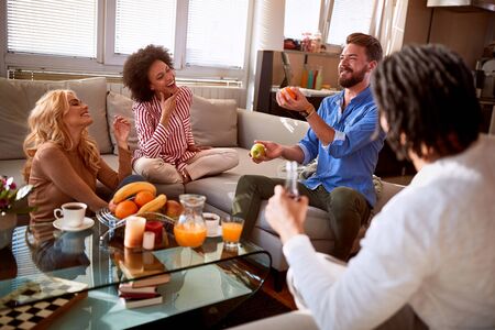 Male entertains friends while juggling with fruitの写真素材