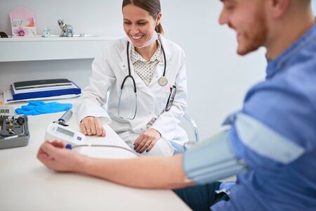 Smiling Doctor  is checking the blood pressure of the man  patient. 
Doctor and patient.の写真素材