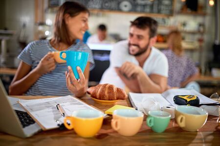 smiling couple opening a cafeteria and choosing cupsの写真素材
