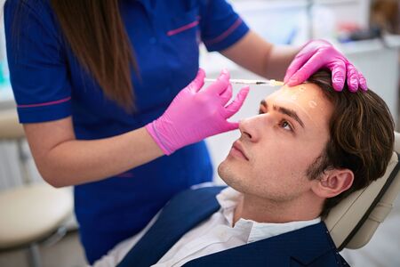 Male having aestetic intervention on his forhend in beauty salonの写真素材