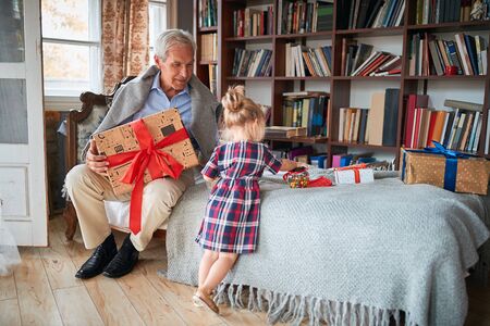 Cheerful girl with her  smiling grandfather enjoying at Christmasの写真素材