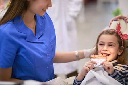 Cute little girl at dentistâs office holding a chocolateの写真素材
