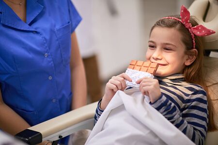 Little girl holding a chocolate, potential teeth hazard or a treat?