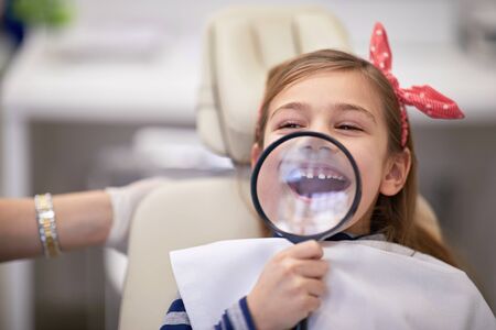 Sweet girl showing her big smile under a magnifying glassの写真素材