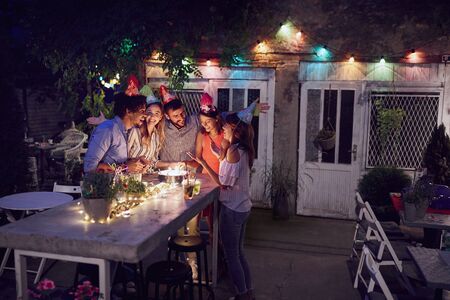 young adults celebrating a birthday party at outdoor cafe. friends, birthday, celebration, outdoor conceptの写真素材