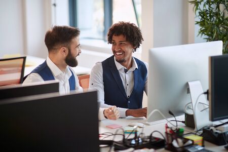 two young colleagues, multiethnic, talking and smiling at the office. business, modern, office,...