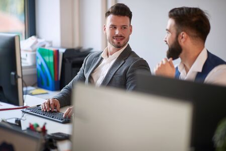 Young business colleagues men talking at work in modern office.の写真素材