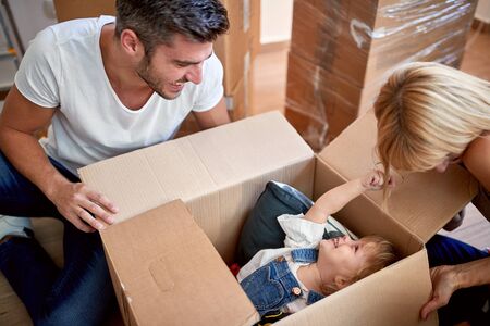 Parents playing with their daughter hiding in cardboard box.の写真素材