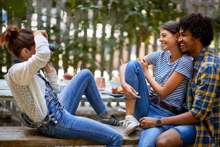 Young woman taking photo of girl and guy outdoorの写真素材