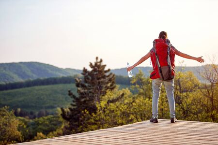 young woman enjoying in nature with arms spread at viewpoint in mountain. positive energy, nature, healing conceptの写真素材