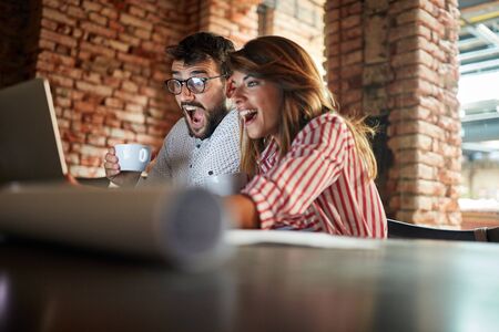 Young men and woman sitting at a cafe,laughing together and enjoying at coffee.