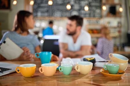 young owners of cafe analyzing different sizes and colors of coffee cups, choosing the right onesの写真素材
