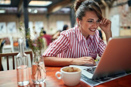 Woman using laptop in cafe.Girl sitting at a cafe,laughing  and enjoying at coffee.の写真素材