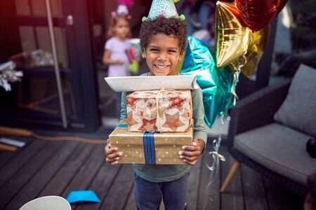 A little boy carrying birthday presents looking at camera.の写真素材