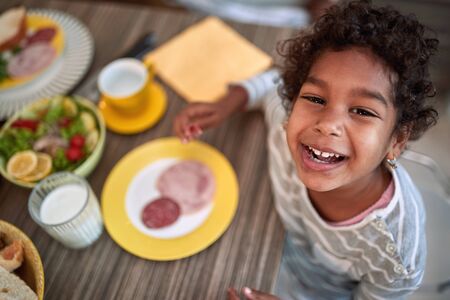 A happy smiling face of young african girl at the kitchen table, having breakfast.の写真素材