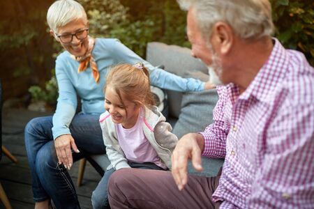 little girl sitting between her grandparents, laughing. Love, affection concept