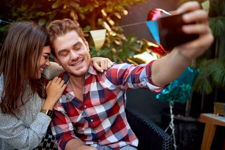 young caucasian couple taking selfie at wrong moment with eyes closed on a birthday partyの写真素材