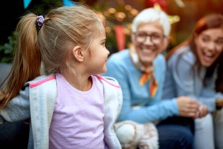 little girl looking at grandmother and mother in the background. Three generation concept