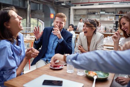 group of young caucasian people laughing at lunch, friends, colleagues, business partners conceptの写真素材