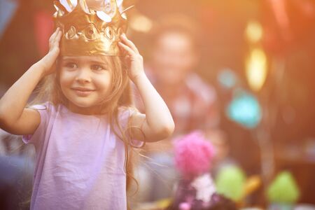 little cute girl with crown at head playing at  birthday party.の写真素材