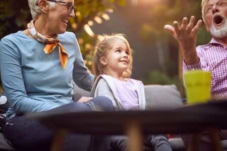 Grandparents playing  with  smiling granddaughter.Girl  enjoying with her grandparents outdoor at...