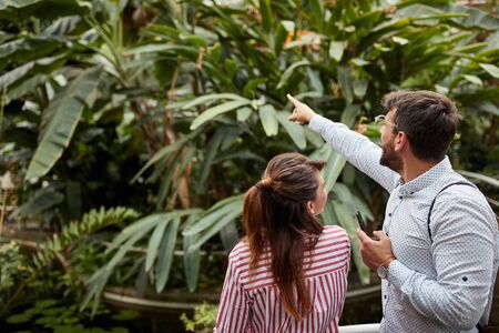 young man showing with index finger different plants to a female, explaining, admiring, enjoying, smiling. Copy spaceの写真素材