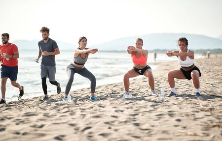 Group of young friends is exercise on the beach by the sea.fitness, sport and healthy lifestyle conceptの写真素材