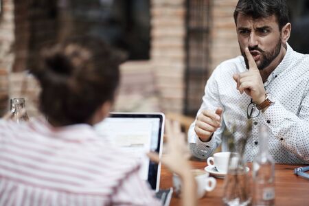 caucasian man showing with his index finger on his mouth to a female to be quiteの写真素材