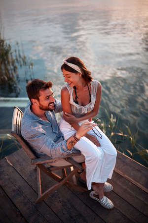 top view of a beautiful woman sitting in a lap of a man by the water, talking, smiling. copy spaceの写真素材
