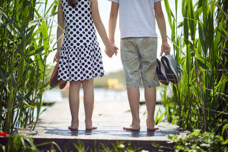 Children near pond. Little boy and girl during  goes on the pond.の写真素材