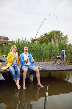 Young man and woman enjoying on fishing together. Fishing on the lake.の写真素材