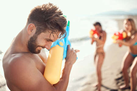two women sprinkle beardy guy with water gunsの写真素材