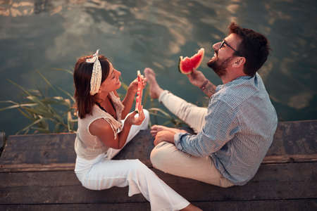top view of young couple sitting  by the river,  eating watermelonの写真素材