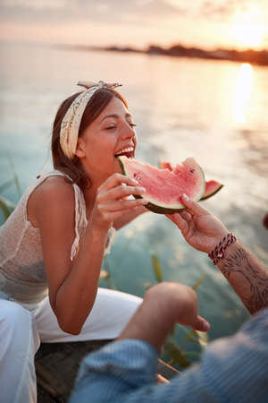 tattooed guy feeding his girlfriend with slice of watermelonの写真素材